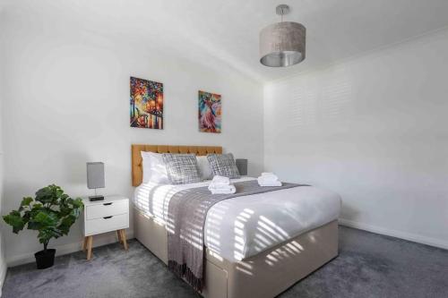 The Orange House Langdon Hills的一间白色的卧室,配有床和盆栽植物