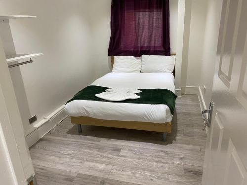伦敦W3 Guest House的一间小卧室,配有白色床单