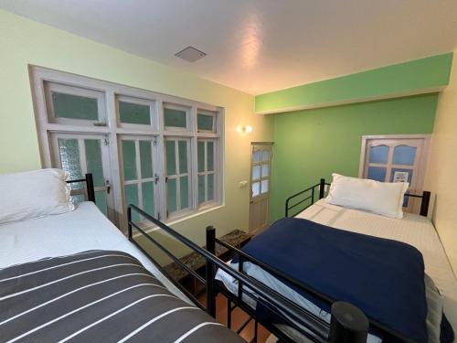 西姆拉Zu-Zu Hostels的配有两张床铺的绿色墙壁和窗户