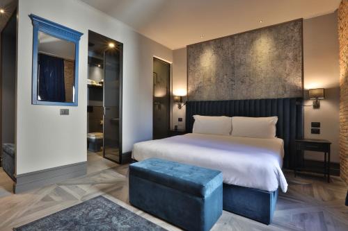 的里雅斯特FORVM bijoux ROOMS的一间卧室设有一张大床和一张蓝色凳子