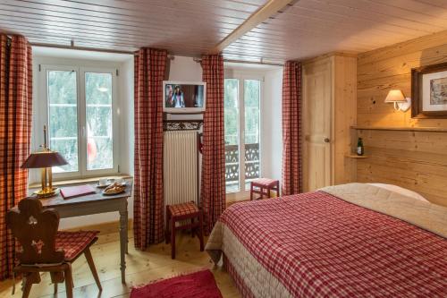 莱迪亚布勒雷Historic Hotel du Pillon的卧室配有一张床、一张书桌和窗户。