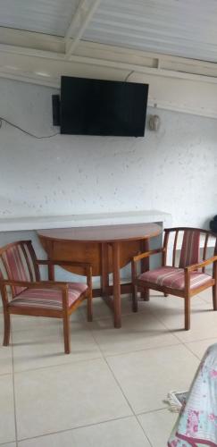 坎皮纳斯Quarto aconchegante Barão Geraldo的一张桌子和两把椅子,墙上有电视