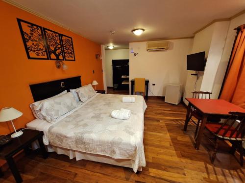 本塔纳山村Grand Hotel - Sierra De La Ventana的一间卧室配有一张床铺和一张桌子,还有一间用餐室