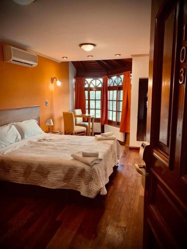 本塔纳山村Grand Hotel - Sierra De La Ventana的卧室配有一张床和一张桌子及椅子