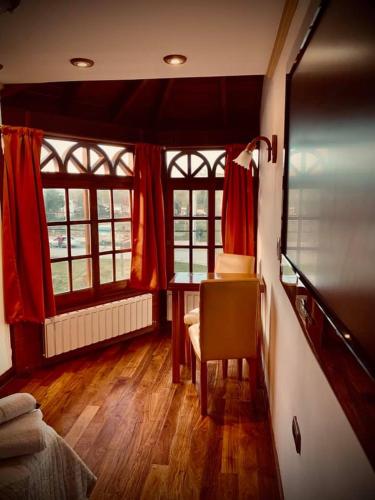本塔纳山村Grand Hotel - Sierra De La Ventana的客房设有书桌、桌子和窗户。