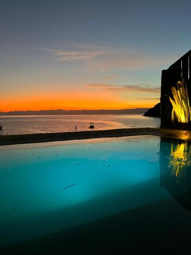 阿拉夏奇巴海滩Casa da Ilha的日落时分享有海洋美景的游泳池