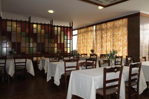 丰沙尔格雷科公寓酒店的用餐室配有白色的桌椅和彩色玻璃窗