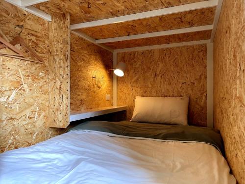 嘉义市日光轻旅 晃拾光 Funtime Hostel的卧室配有一张床铺,位于带木墙的房间内