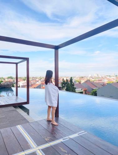 PulosirihGrand Kamala Lagoon Bekasi Apartement - Type Studio的站在甲板上看游泳池的女人