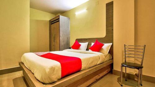 贾姆谢德布尔OYO Flagship Dream Connect的一间卧室配有一张带红色枕头的床和一把椅子