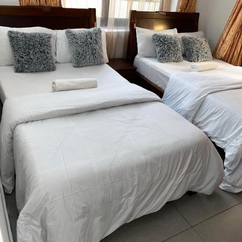 达累斯萨拉姆En-Suite Rooms W/Pool & Gym in Mikocheni Near Beach的配有2张床的带白色床单和枕头的客房