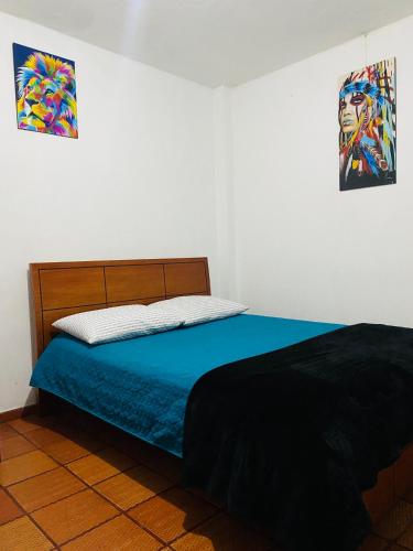 波哥大Bogotá Kings 101的一间卧室配有一张带蓝色床单和绘画的床。