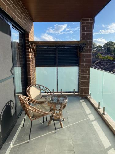 悉尼Penshurst Guest House的阳台的天井配有桌椅