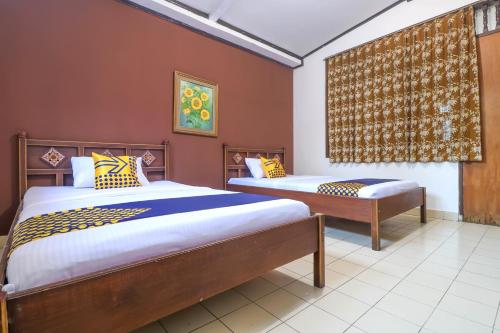 登巴萨SUPER OYO 1927 Hotel Candra Adigraha的一间卧室设有两张床和窗户。