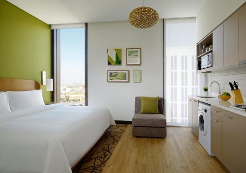 迪拜Element Me'aisam, Dubai的一间带白色大床的卧室和一间厨房