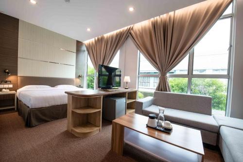 山打根Hotel Meliden的酒店客房配有床、沙发和电视。