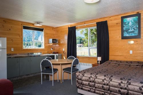 福克斯冰川福克斯冰川TOP 10假日公园及汽车旅馆的一间卧室配有一张床铺和一张桌子,还设有一间厨房