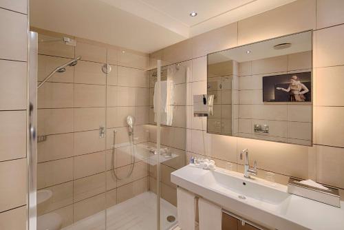 米兰米兰丽笙酒店的带淋浴、盥洗盆和镜子的浴室