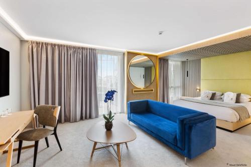 贡比涅Aiden by Best Western T'aim Hotel的酒店客房配有蓝色的沙发和床。