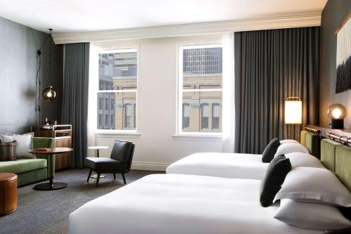 西雅图The Alexis Royal Sonesta Hotel Seattle的酒店客房,配有两张床和椅子