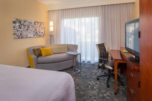 夏洛特夏洛特大学研究园万怡酒店的酒店客房配有一张床、一张沙发和一张书桌。