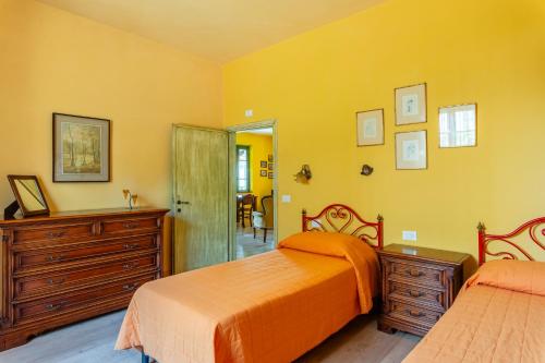 PopiglioTramonto al Rifugio Arcobaleno的黄色卧室配有两张床和梳妆台
