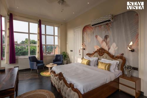 新德里StayVista's Indraj Manor - Roman-Inspired Villa with Posh Interiors, Mesmerizing Garden & Outdoor Fireplace的一间卧室设有一张大床和大窗户
