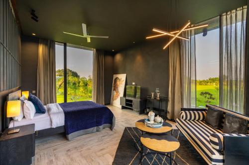 新德里StayVista's Anantam - Villa with Massive Outdoor Pool with Deck & Sprawling Lawn的一间卧室配有一张床、一张沙发和一台电视。