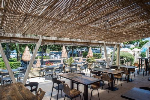 Salles-CuranParc du Charouzech的一间设有桌子和椅子的稻草屋顶餐厅