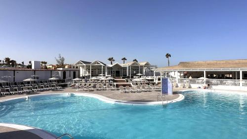 卡勒达德福斯特卡勒塔多拉达公寓的酒店的大型游泳池配有桌椅