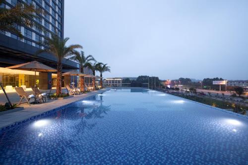 莆田莆田秀屿假日酒店的一座棕榈树大型游泳池和一座建筑