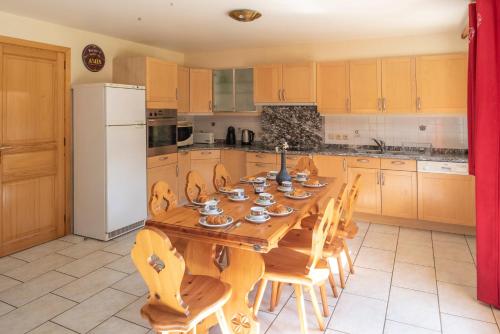 莱热Chalet R'Mize的厨房配有带椅子的木桌和白色冰箱。