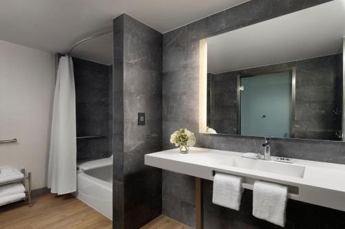 普莱森顿AC Hotel by Marriott Pleasanton的浴室配有盥洗盆、镜子和浴缸