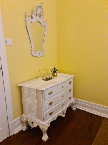 波尔图Casinhas no Carolina - Hostel的黄色房间的一个白色梳妆台,带有镜子