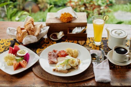 乌布Moringa Ubud Villa的一张桌子,上面放着两盘早餐食品和一杯橙汁