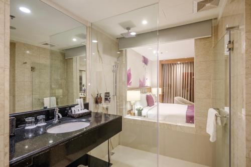 马尼拉Eastwood Richmonde Hotel - Newly Renovated的一间带水槽和镜子的浴室以及一张床