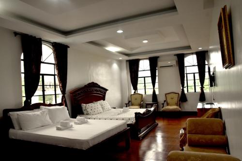 MamburaoIsla De Oro Hotel的一间卧室设有两张床、一张沙发和窗户。