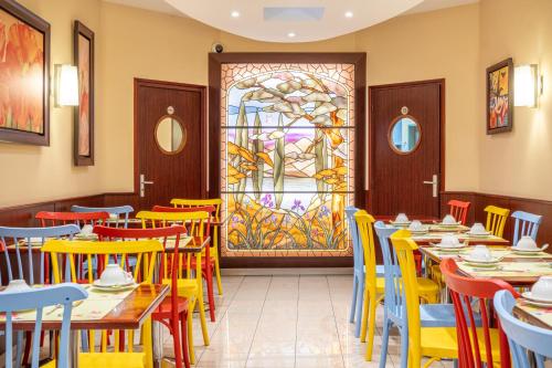 巴黎蒙帕纳斯总站酒店的餐厅设有桌椅和彩色玻璃窗