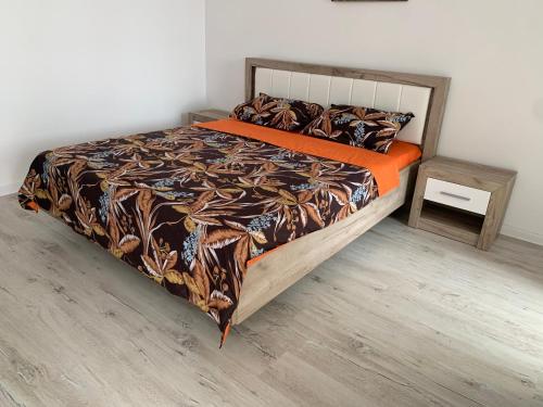 RoşuResidence Tineretului的一张带橙色棉被和边桌的床