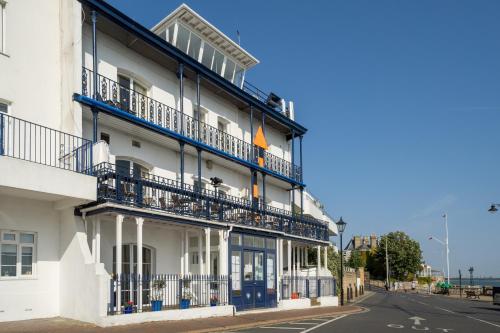 West CowesRoyal London Yacht Club的白色的建筑,设有蓝色的阳台,位于街道上