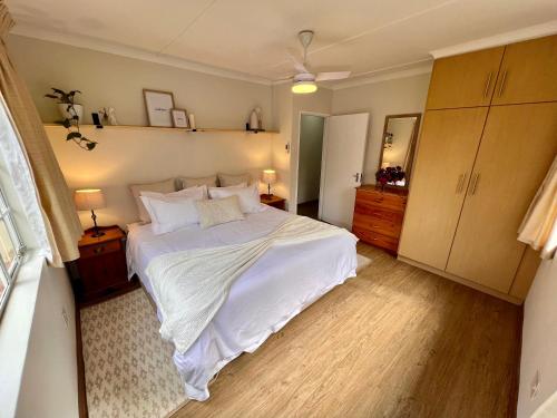 温特顿Berg Escape Bottlebrush - Spacious Luxury Family Home的卧室配有一张带白色床单和木地板的大床。