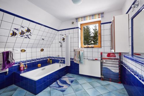 拉布卡Drewniany Dom Rabka Zdrój的蓝色和白色的浴室设有浴缸和窗户。
