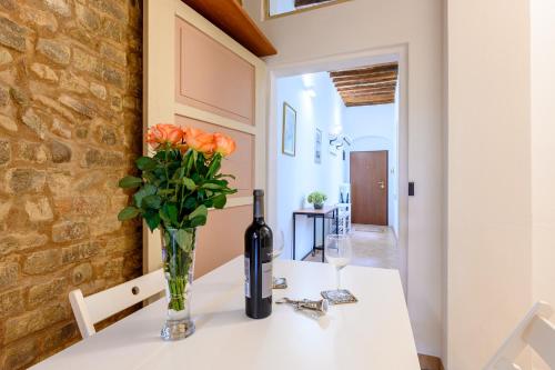 帕尔马Parma Parco Ducale Cozy Apartment的一张桌子,上面放着一瓶葡萄酒和鲜花