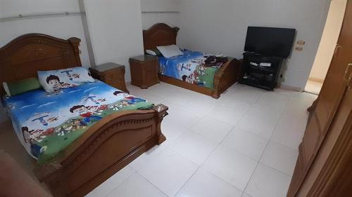 开罗شقة مفروشة للايجار فندقية جنينة مول الرئيسي的一间卧室配有两张床和一台平面电视