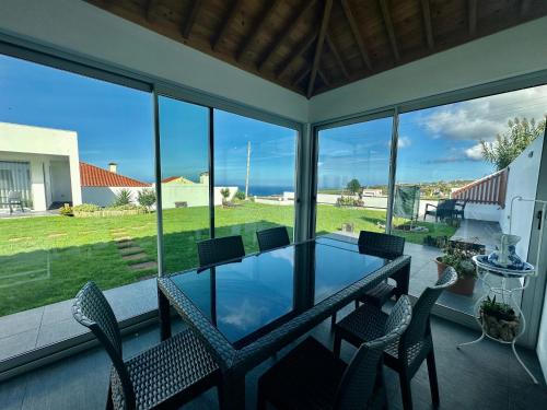 NordestinhoSerenity Azores - Casa da Aldeia的门廊上设有玻璃桌和椅子,
