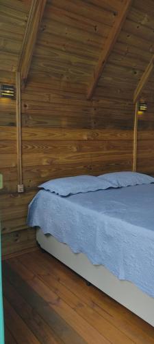 帕萨夸特鲁Chácara do sossego的卧室配有木墙内的一张床