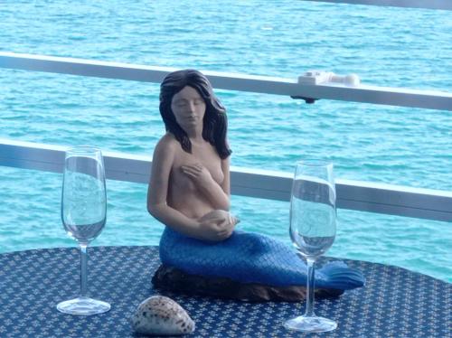 库列拉apartamento junto al mar的坐在桌子上的女人的雕像,配上两杯酒杯