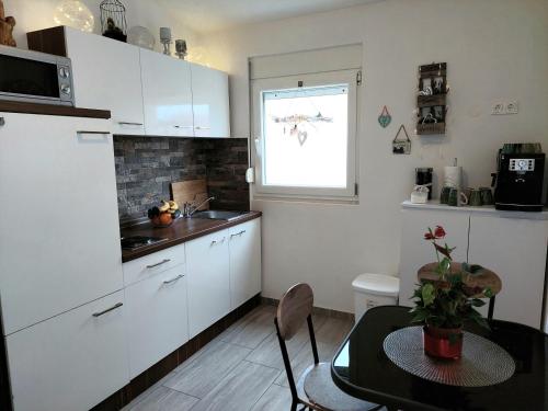 维尔Villa Colonia Vir的厨房配有白色橱柜、桌子和窗户。