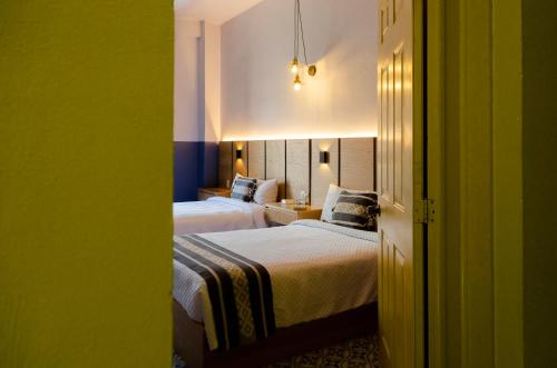 瓦哈卡市Hotel Casona Oaxaca的绿墙旅馆客房的两张床