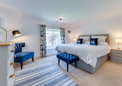 BrundallThe Firs的一间卧室配有一张大床和一张蓝色椅子